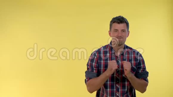 兴奋的男人穿着格子衬衫举起拳头在黄色的背景下欢呼视频的预览图