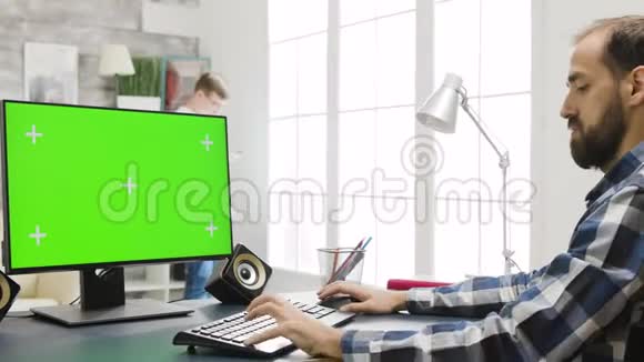 在舒适明亮的客厅里使用绿色屏幕的个人电脑显示器视频的预览图
