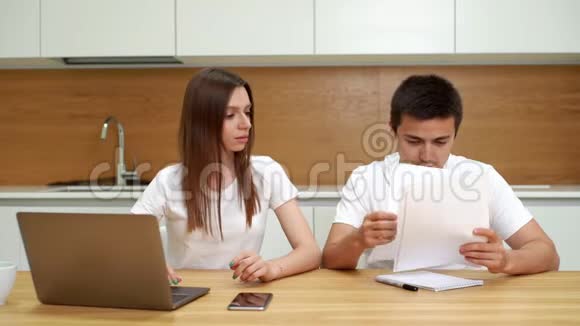 夫妻俩坐在餐桌旁使用笔记本电脑打理公用事业账单视频的预览图