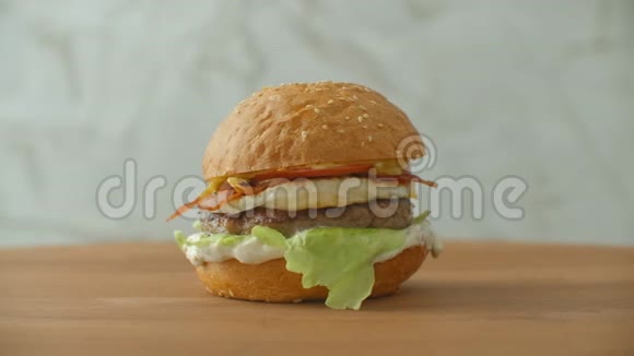 一个大的美味汉堡里面有肉馅饼洋葱蔬菜融化奶酪生菜视频的预览图