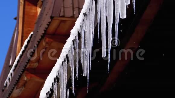 冰柱融化并滴在太阳上挂在木屋的屋顶上慢动作视频的预览图