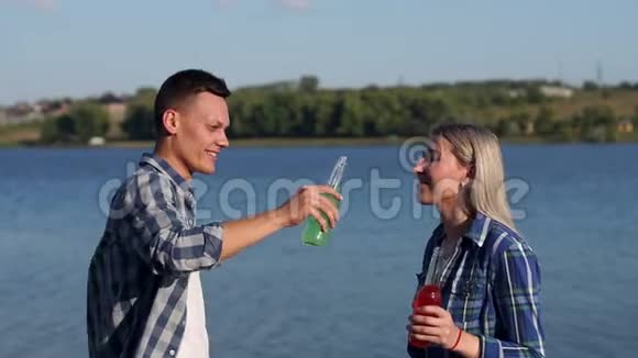 年轻人喝酒精饮料嘲笑湖的背景视频的预览图