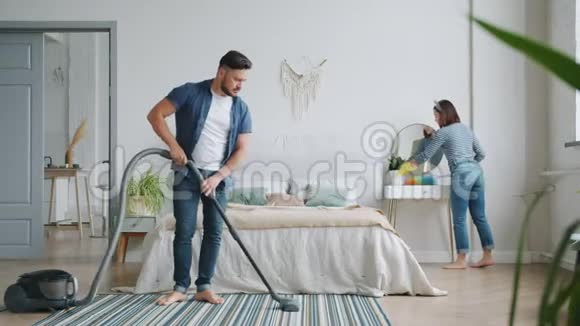 男人和女人在卧室的清洁室里忙着做家务用吸尘器打扫视频的预览图