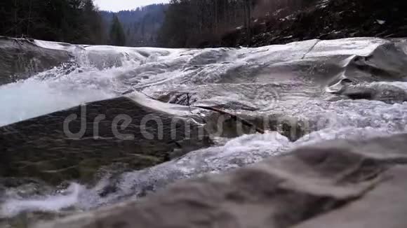 山溪和石急流与雪水的快速流动冬季瀑布慢动作视频的预览图