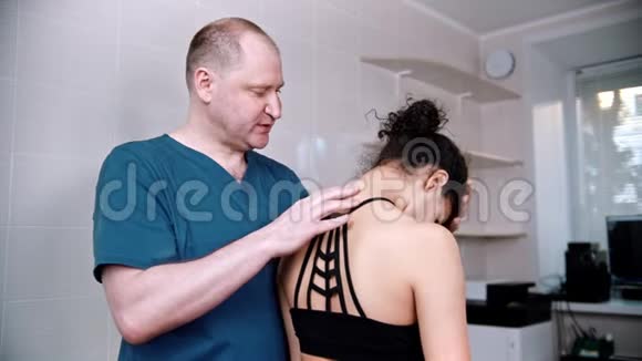 脊椎治疗医生在手术前检查年轻妇女上下弯曲颈部视频的预览图