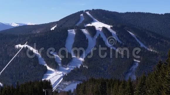 滑雪者在阳光明媚的一天在滑雪场的雪坡上骑马视频的预览图