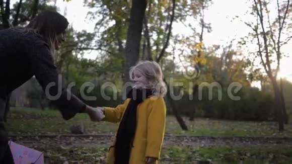 和一个孩子玩妈妈和一个微笑的女孩在秋天公园里玩石头剪刀玩视频的预览图