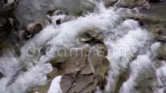 快速水流从山溪和石急流与雪冬天的瀑布普鲁特视频的预览图