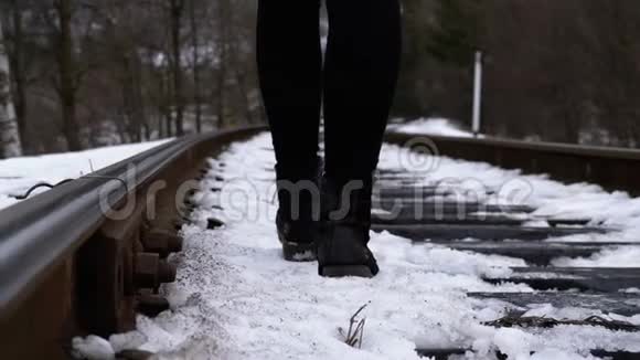 一个女孩在冬天沿着旧铁轨行走的腿慢动作视频的预览图