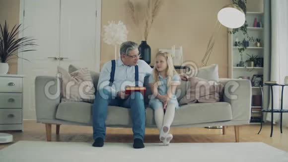 小女孩和她爷爷正在看书视频的预览图