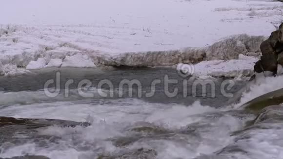 冬天雪从山溪和石急流中快速流出的水瀑布慢动作视频的预览图