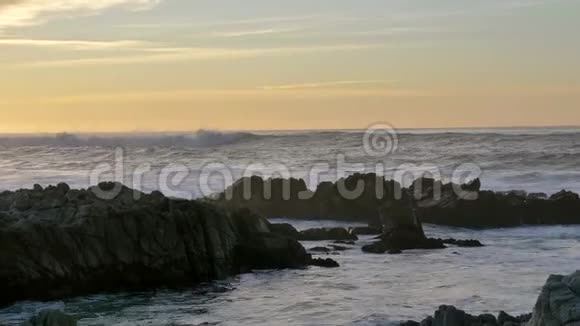 在太平洋格罗夫PacificGrove日落的天空下在多岩石的海岸上一波一波缓慢移动的泛右太平洋海浪在翻滚和破碎视频的预览图