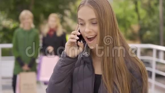 一幅白种人女人在后台等着她的两个女朋友用手机说话的正面画像视频的预览图