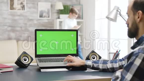 年轻人看着带有彩色绿色屏幕模型的笔记本电脑视频的预览图
