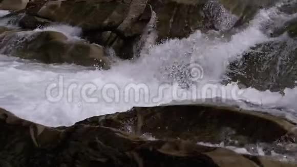 山溪和石急流与雪水的快速流动冬季瀑布慢动作视频的预览图