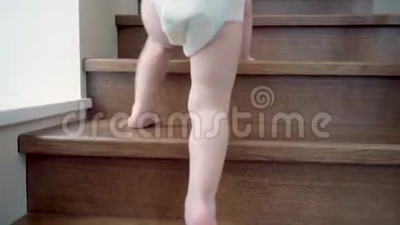 特写镜头一个孩子光着脚用锻铁栏杆快速爬上一个木制楼梯视频的预览图