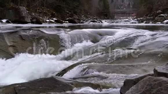 山溪和石头急流与雪水的快速流动冬季瀑布慢动作视频的预览图