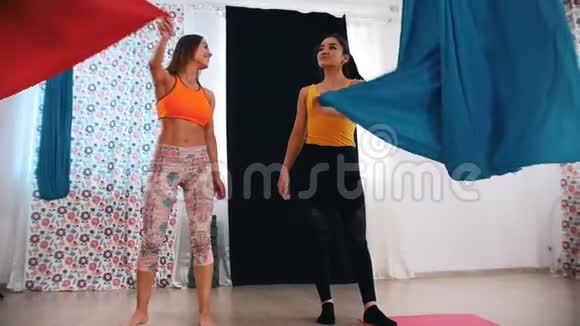 空中瑜伽两个女人准备训练铺上明亮的吊床布视频的预览图