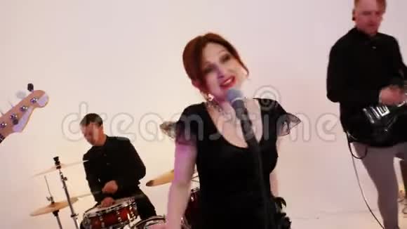 一个吸引人的乐队四个穿着黑色衣服的人在明亮的工作室里演奏歌曲拍摄一首动态音乐视频的预览图