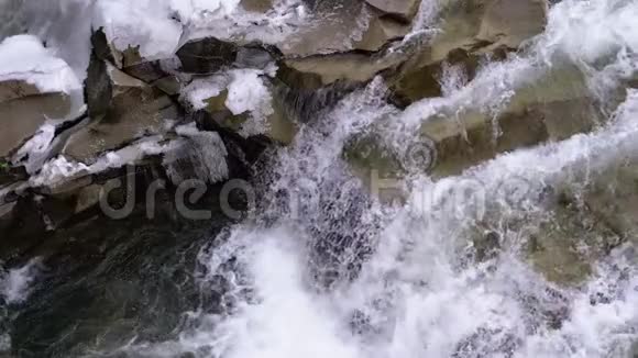 山溪和石头急流与雪水的快速流动冬季瀑布慢动作视频的预览图