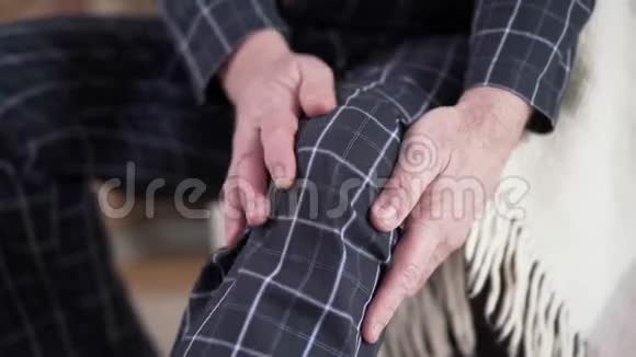 成熟男性白种人穿着睡衣揉膝的特写镜头患有疼痛的高级退休人员生活方式衰老视频的预览图