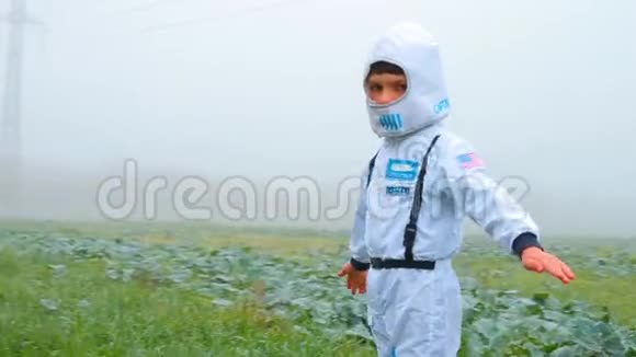 一个穿着白色西装的男孩站在一片雾蒙蒙的田野里探索地球视频的预览图