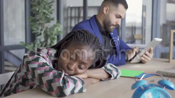 非裔美国妇女打盹等待高加索男性设计师在他的平板电脑上制作这个项目视频的预览图