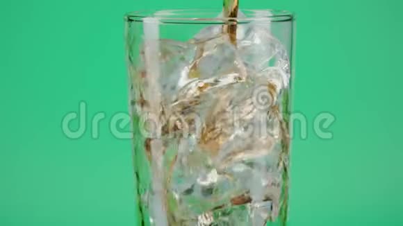 将可乐倒入装有冰块的玻璃杯中置于绿色背景下特写镜头对准红色视频的预览图