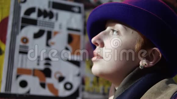 女人的脸戴着蓝色的帽子背景上看着海报贴着现代的城墙视频的预览图