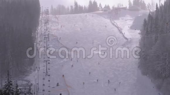 在阳光明媚的日子里滑雪者和滑雪者在滑雪场的雪坡上骑马视频的预览图