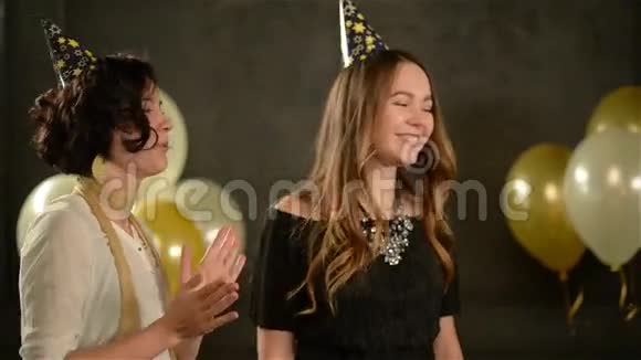微笑美丽的女孩在巧克力蛋糕上吹蜡烛和她的两个朋友一起玩女人歌唱生日快乐视频的预览图
