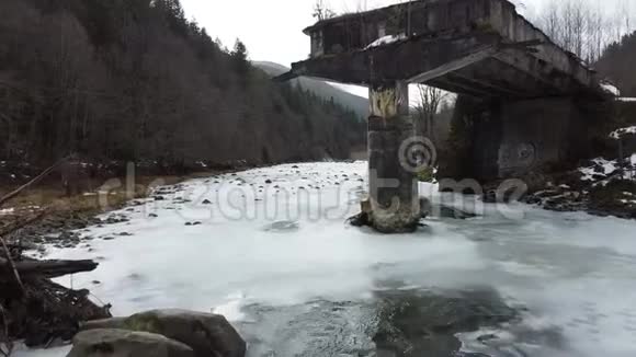 一条半冻的河流过一座破旧的桥塔视频的预览图