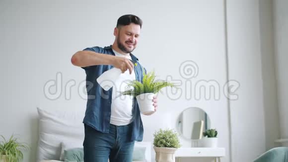 帅哥在家里用喷壶浇植物享受家务视频的预览图