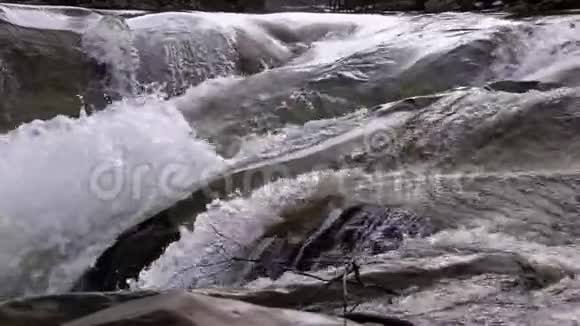 山溪和石头急流与雪水的快速流动冬季瀑布慢动作视频的预览图