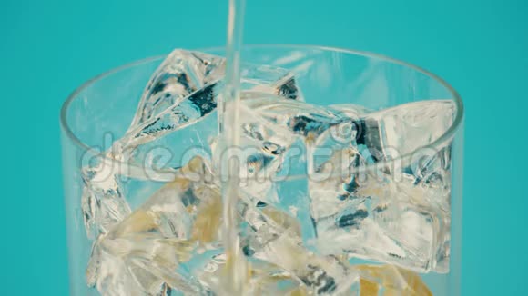 将柠檬水倒入带有冰块的玻璃杯中置于青色背景下特写镜头对准红色视频的预览图