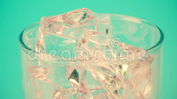 将红色饮料倒入装有冰块的玻璃杯中置于青色背景下特写镜头对准红色视频的预览图
