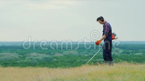 一个人在风景如画的地方用修剪器割草视频的预览图