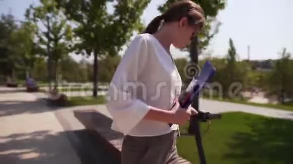 年轻漂亮的女士穿着商务服手里拿着一个文件夹在工作休息时坐在公园的长椅上视频的预览图