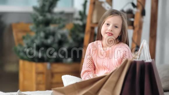 微笑的小可爱女孩在温馨的家摆着圣诞礼物购物袋的画像视频的预览图