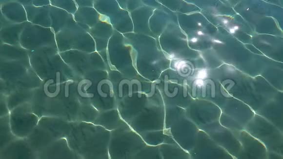 底部可以看到绿松石海有阳光反射和清澈的水沙子和小鱼慢动作视频的预览图