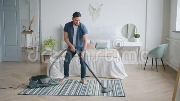 在家里打扫卫生时使用吸尘器的开朗男人跳舞快乐视频的预览图