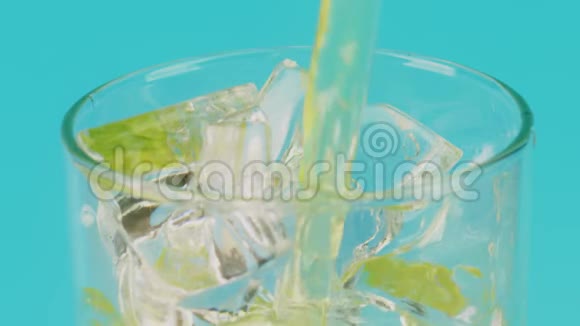 将软饮料倒入盛满冰块的玻璃杯中置于青色背景下视频的预览图