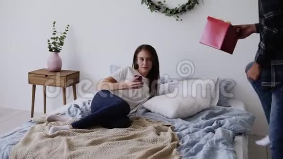 男朋友在家里的床上给他女朋友送礼物对一个有爱的人来说有点惊讶白色床单视频的预览图