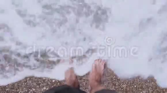 雄脚沿着海滨走雄性喜欢在卵石海滩上的海浪一个男人喜欢在鹅卵石滩上放松视频的预览图