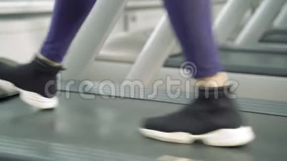 在健身房的跑步机上穿着运动鞋的女性腿视频的预览图