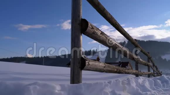 古老废弃的木栅栏和白雪皑皑的木屋和群山的冬季乡村景象视频的预览图