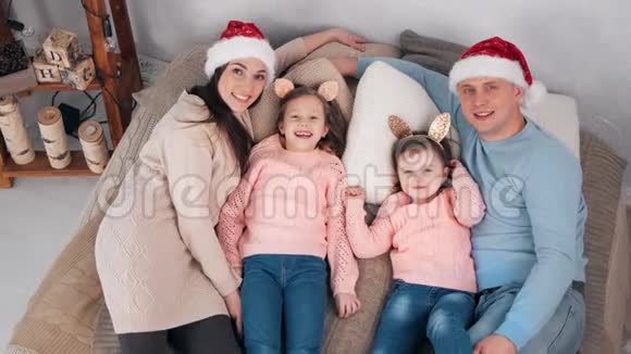 顶景欢乐喜庆的一家人躺在床上围着圣诞老人的帽子玩得开心视频的预览图
