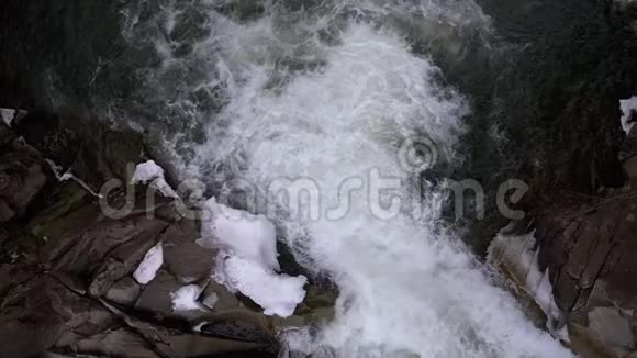 山溪和石头急流与雪水的快速流动冬季瀑布慢动作视频的预览图