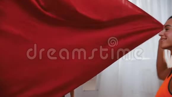 空中瑜伽一个爱运动的微笑的女人铺着红色吊床的布做瑜伽视频的预览图