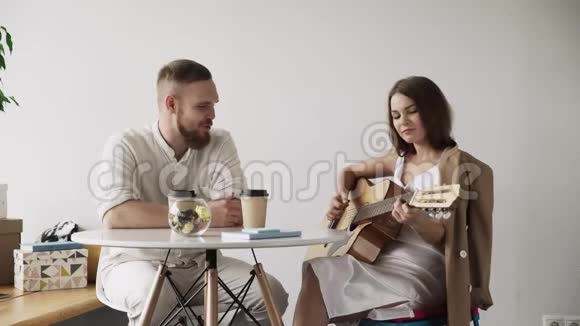年轻的时髦女人在咖啡馆里弹吉他唱一首歌给她的朋友听视频的预览图
